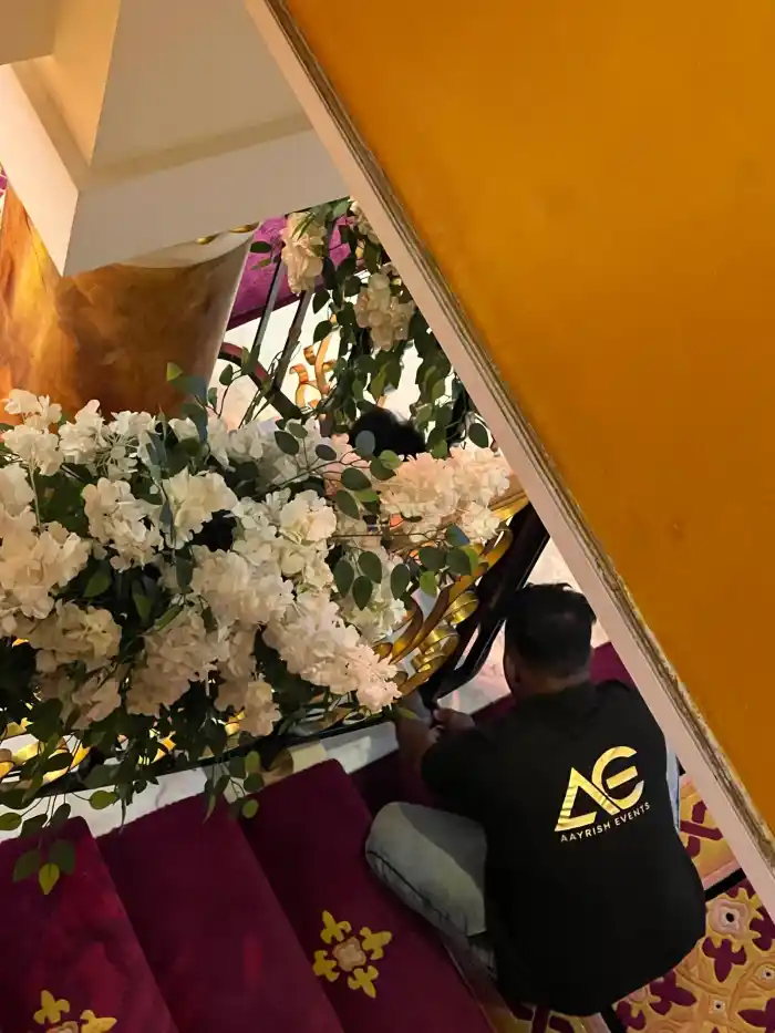 An Aayrish Events florist fixing white hydrangea and foliage to a ballroom staircase rail