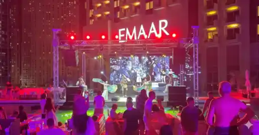 Dancers performing on a poolside stage under red and purple lighting at night